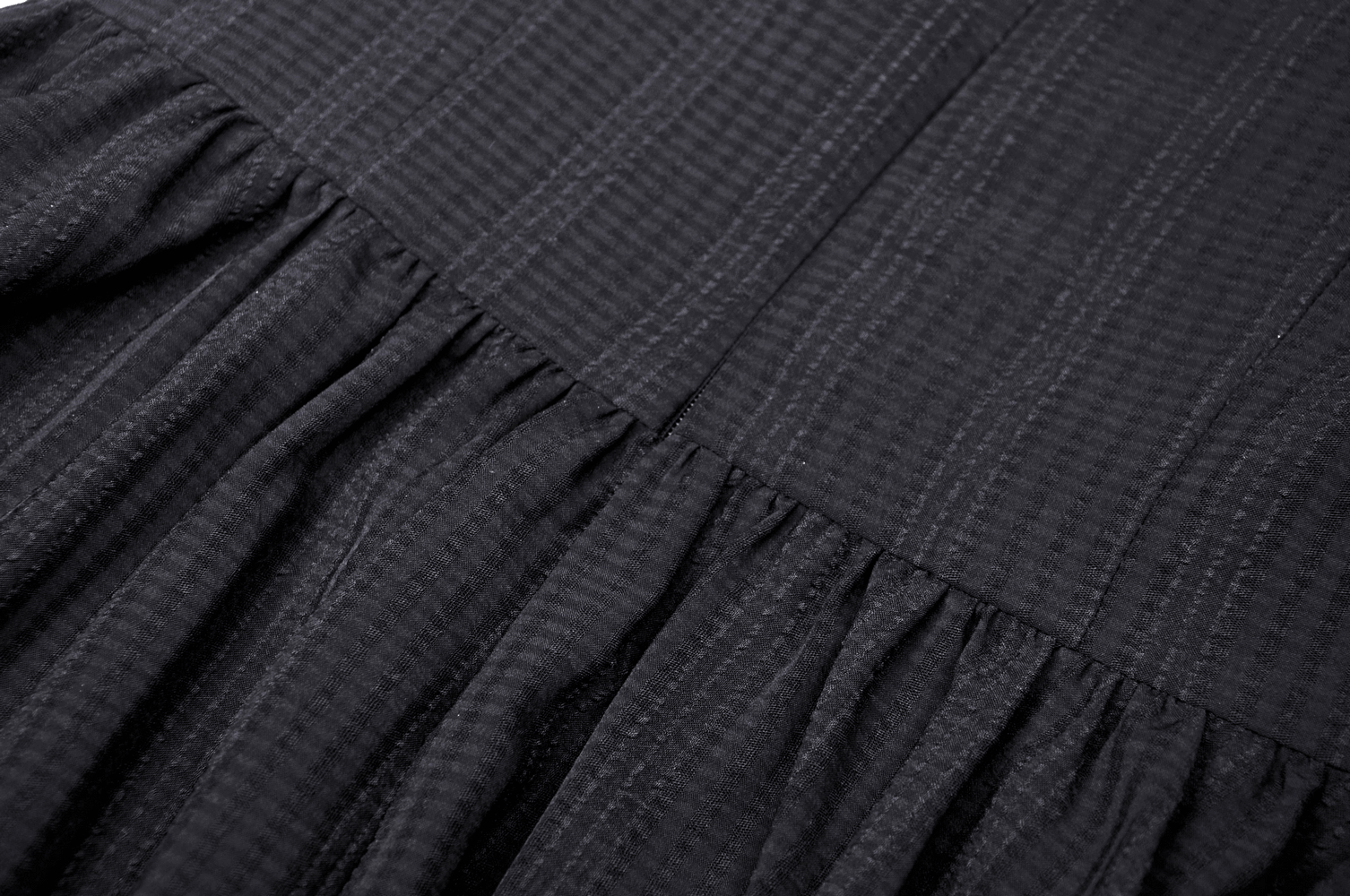 Close-up of black textured fabric showcasing pleats, perfect for a Gothic Lolita dress with a dark, romantic vibe.