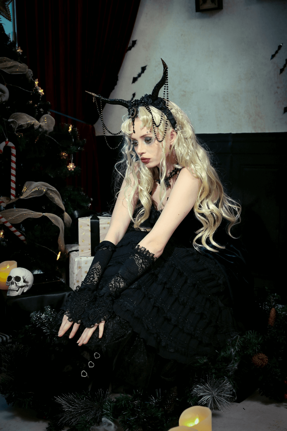 Gothic Lolita model with long blonde hair wearing a black dress and lace gloves, surrounded by festive decorations.