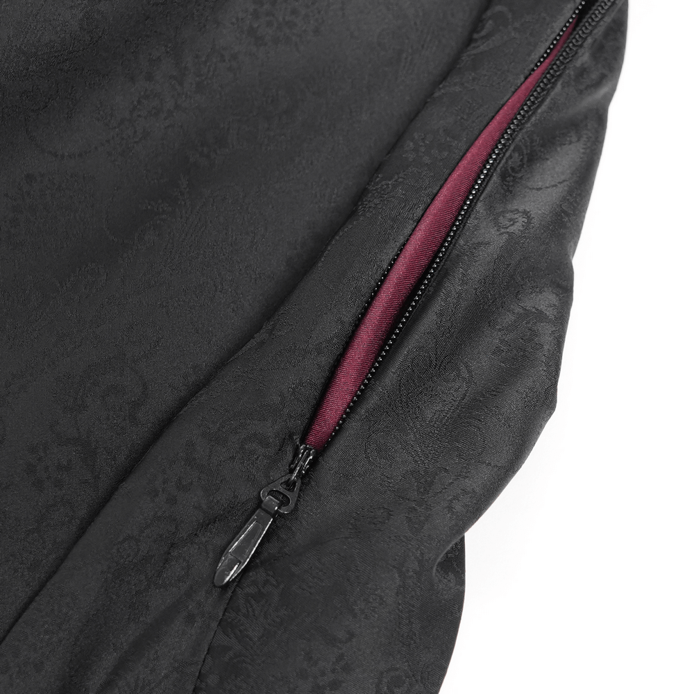 Close-up of a black fabric with intricate design and a wine red zipper detail, showcasing gothic dress craftsmanship.