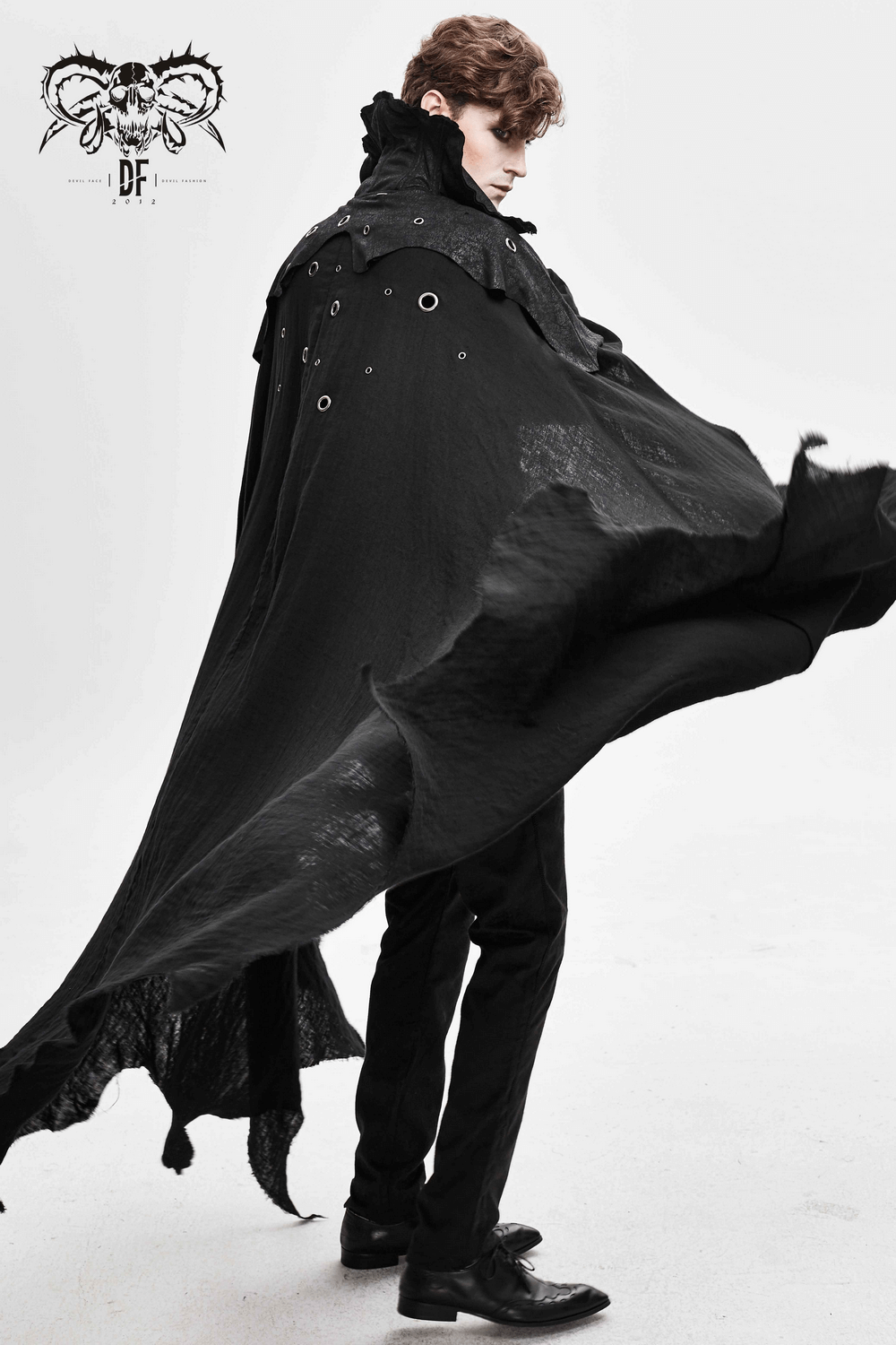 Elegant male model wearing a gothic long black cloak with stand-up collar and dramatic flowing sleeves.