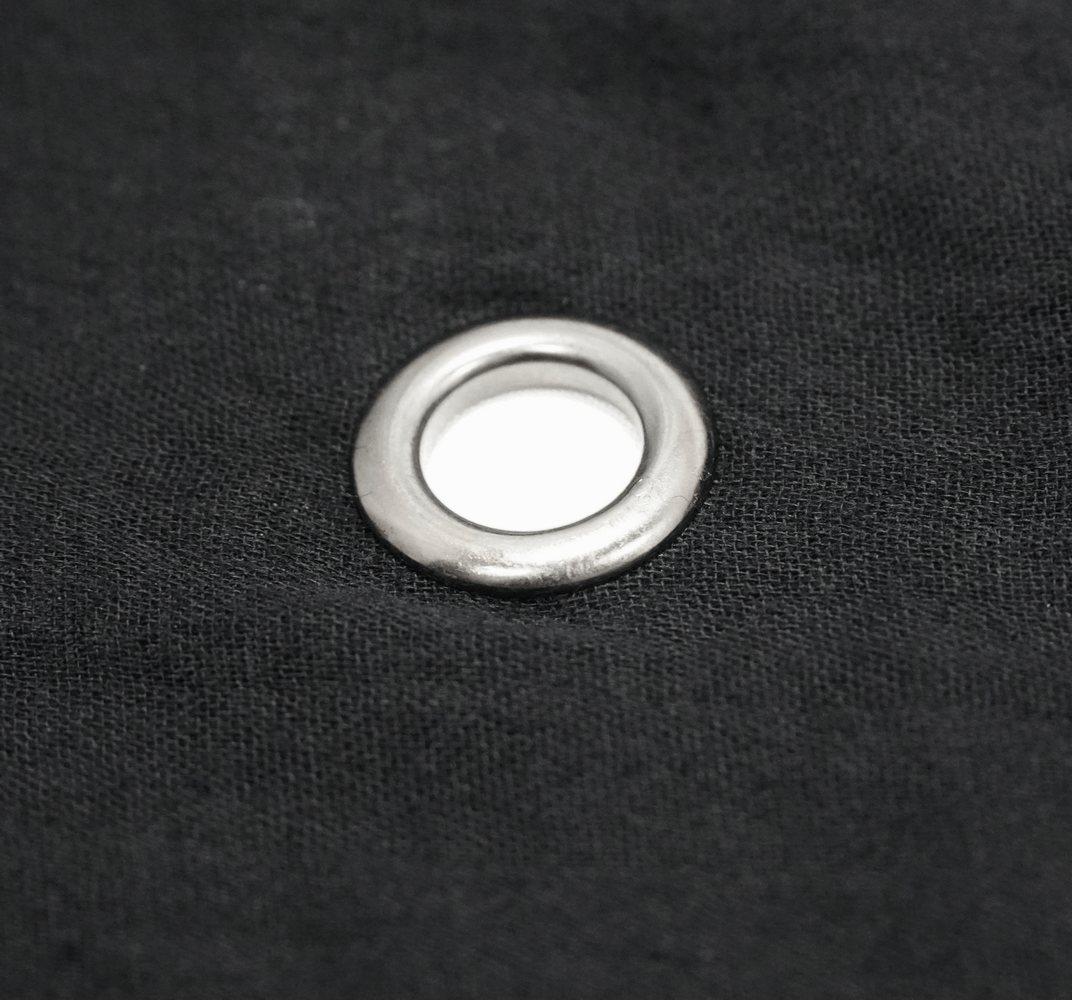 Close-up of a silver grommet on black fabric, perfect detail for gothic outerwear or cloaks.