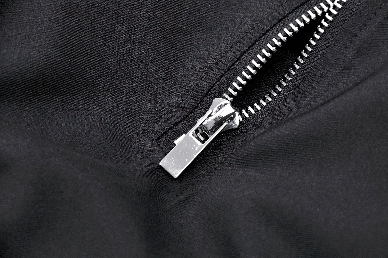 Close-up of a silver zipper on a black fabric, showcasing the sleek design of a gothic long skirt.