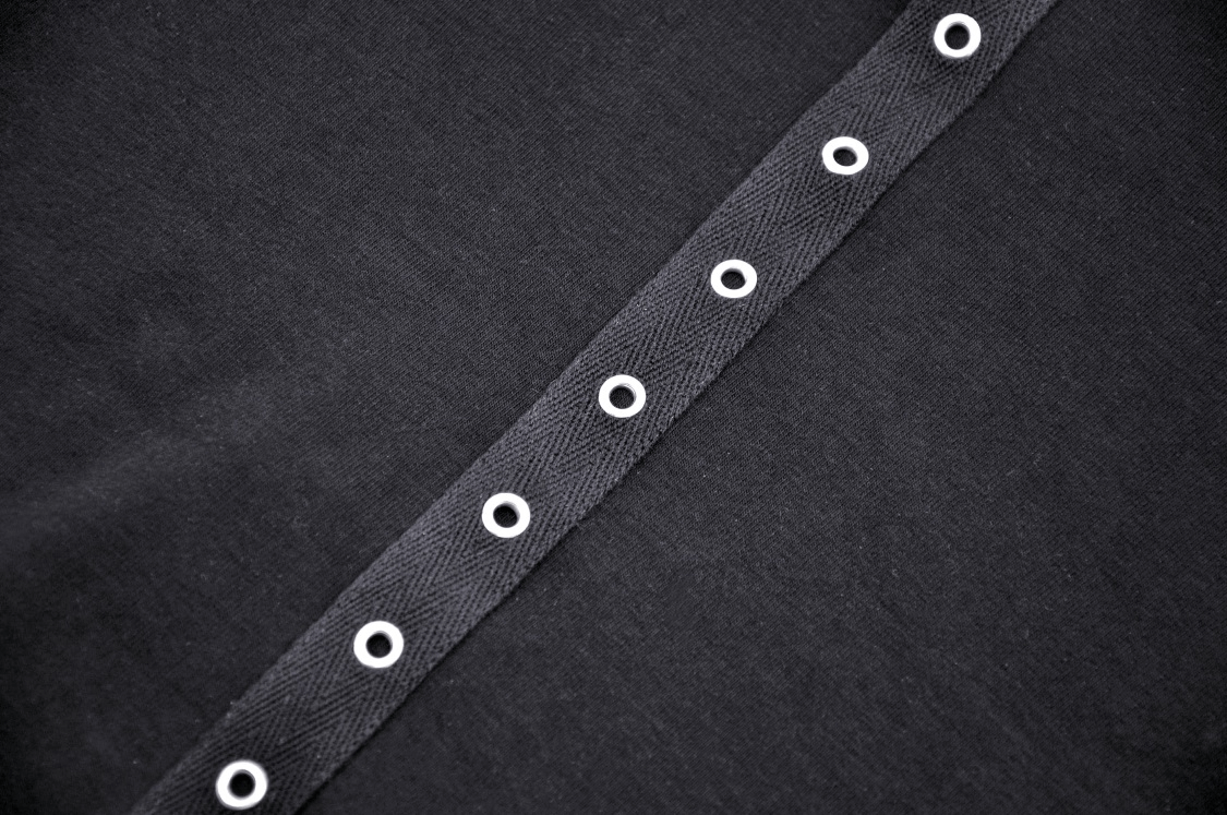 Close-up of black crop top featuring eyelets, showcasing gothic and edgy design elements.