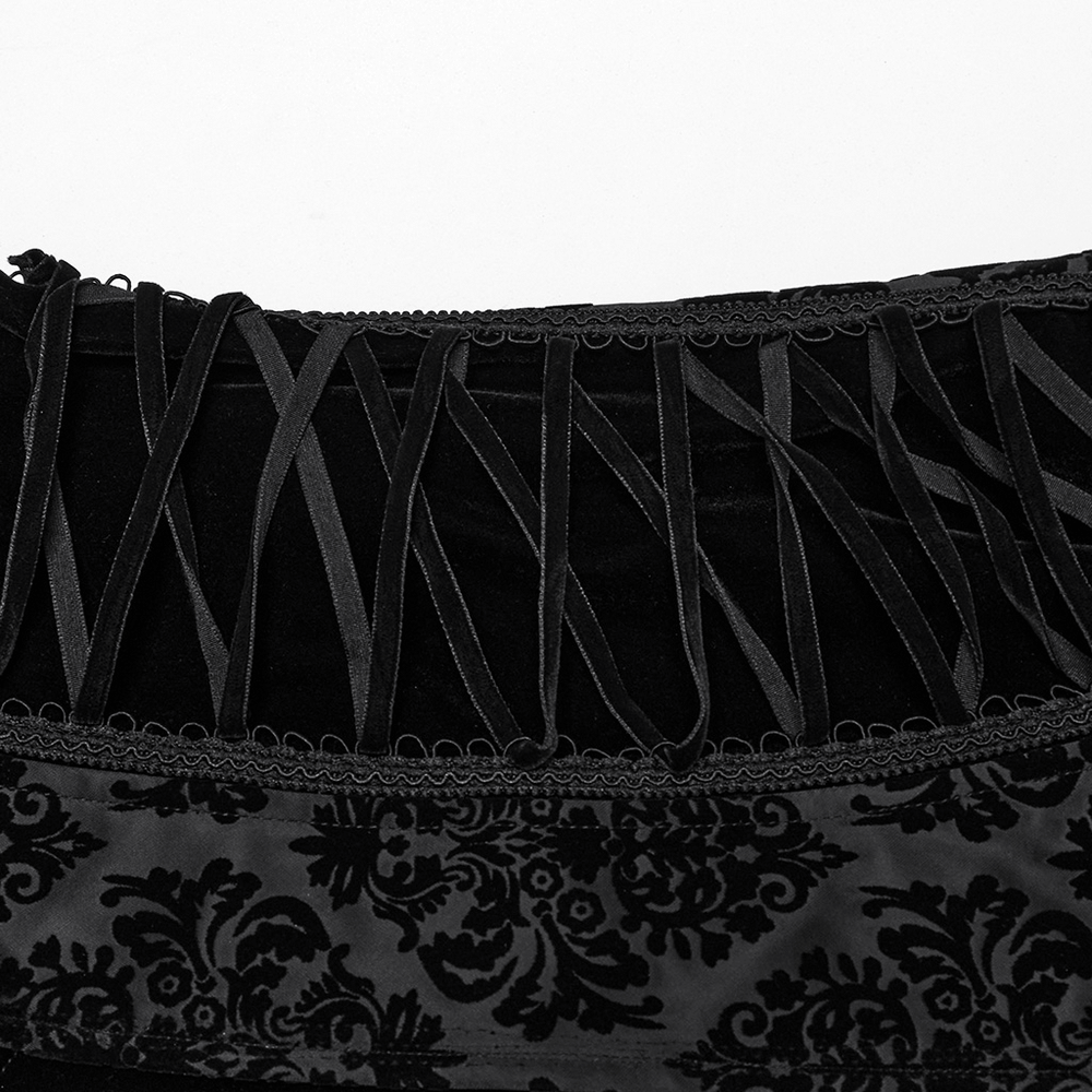 Close-up of gothic waistcoat detailing featuring intricate flocking patterns and velvet webbing accents.