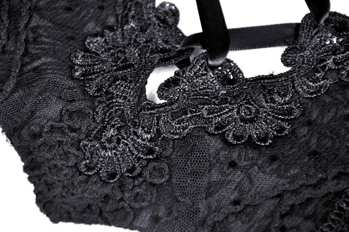 Close-up of elegant black lace detailing on a Gothic luxe corset with garters, showcasing intricate floral patterns.