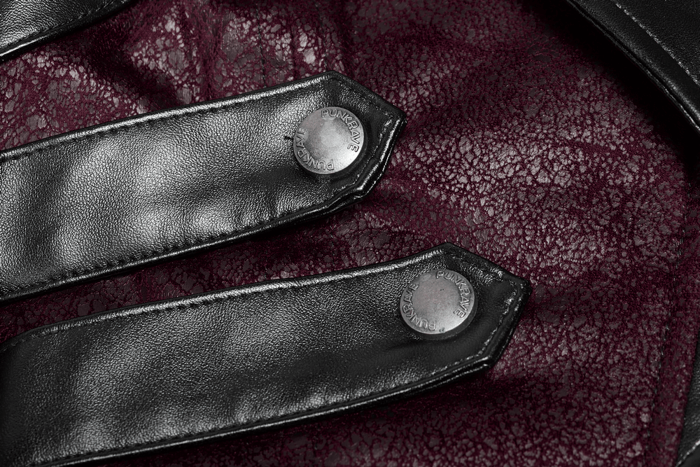 Close-up of black straps with metallic buttons on a burgundy leather background, highlighting gothic elegance.