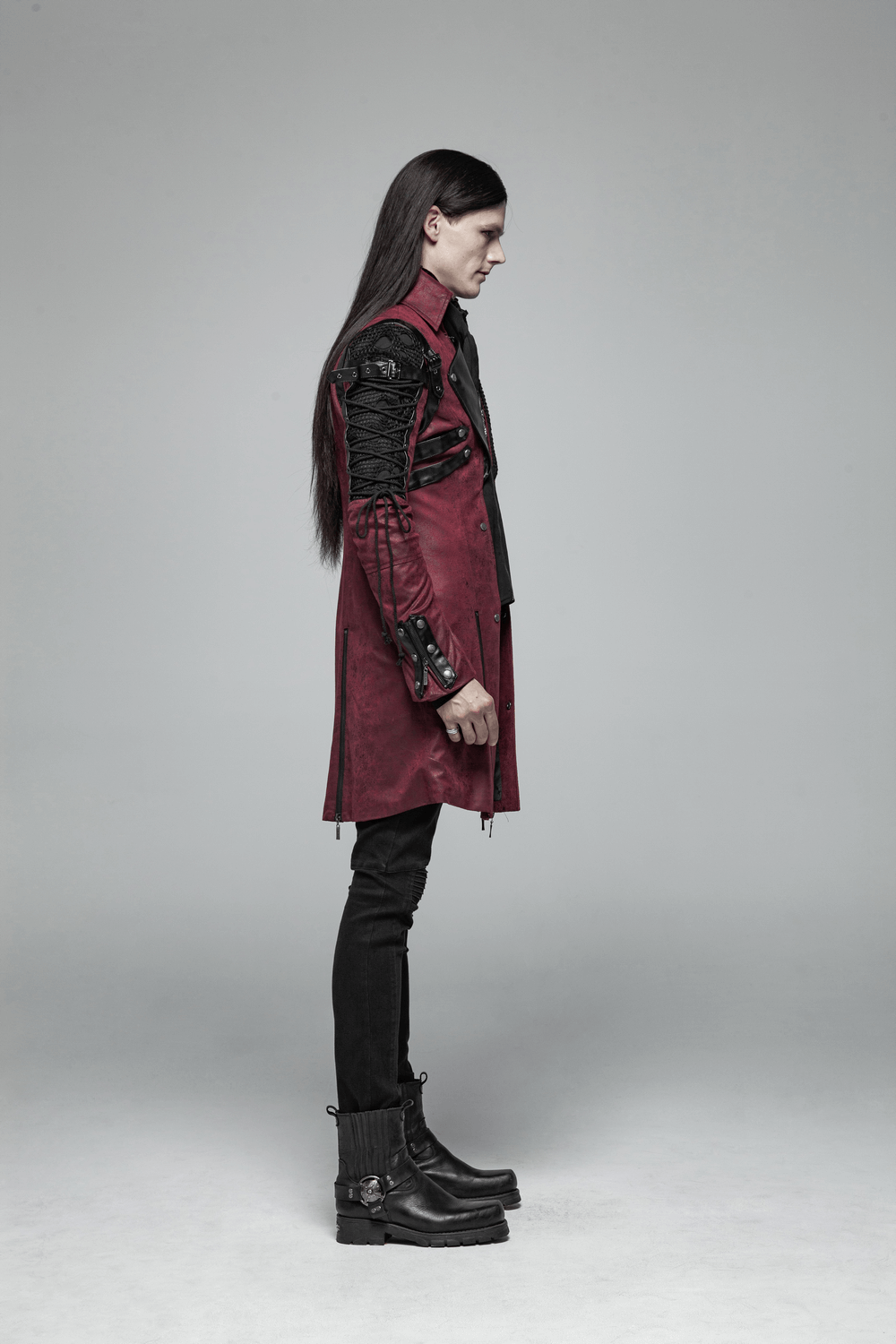 Gothic male model in a burgundy leather trench coat with laced sleeves, showcasing edgy Victorian elegance.