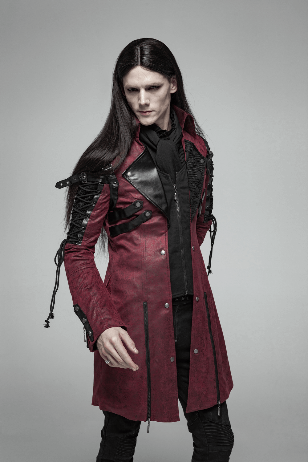 Gothic male model in burgundy leather trench coat with laced sleeves, showcasing Victorian elegance and mystery.