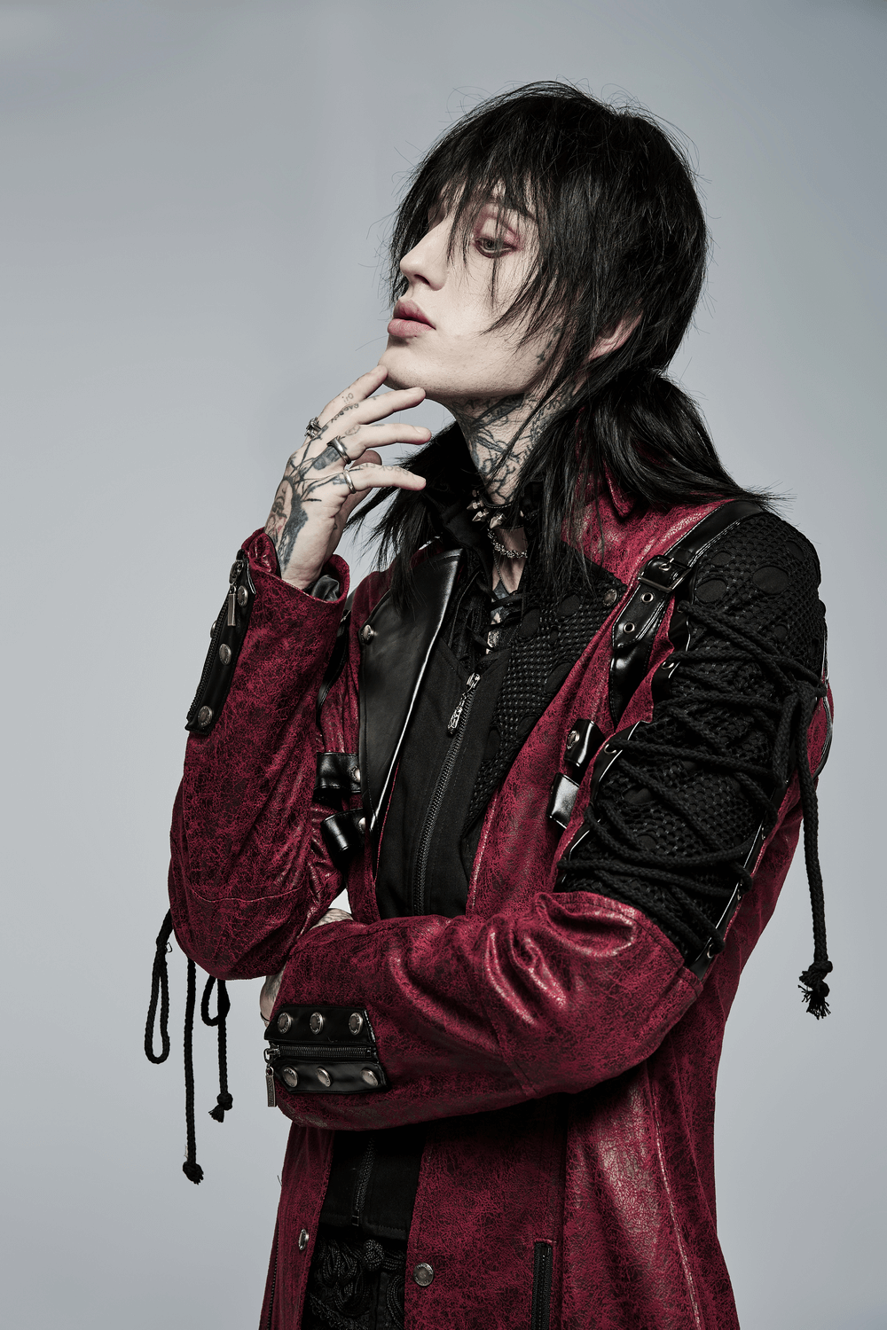 Gothic elegance: model showcasing a burgundy leather trench coat with laced sleeves and dark, mysterious style.