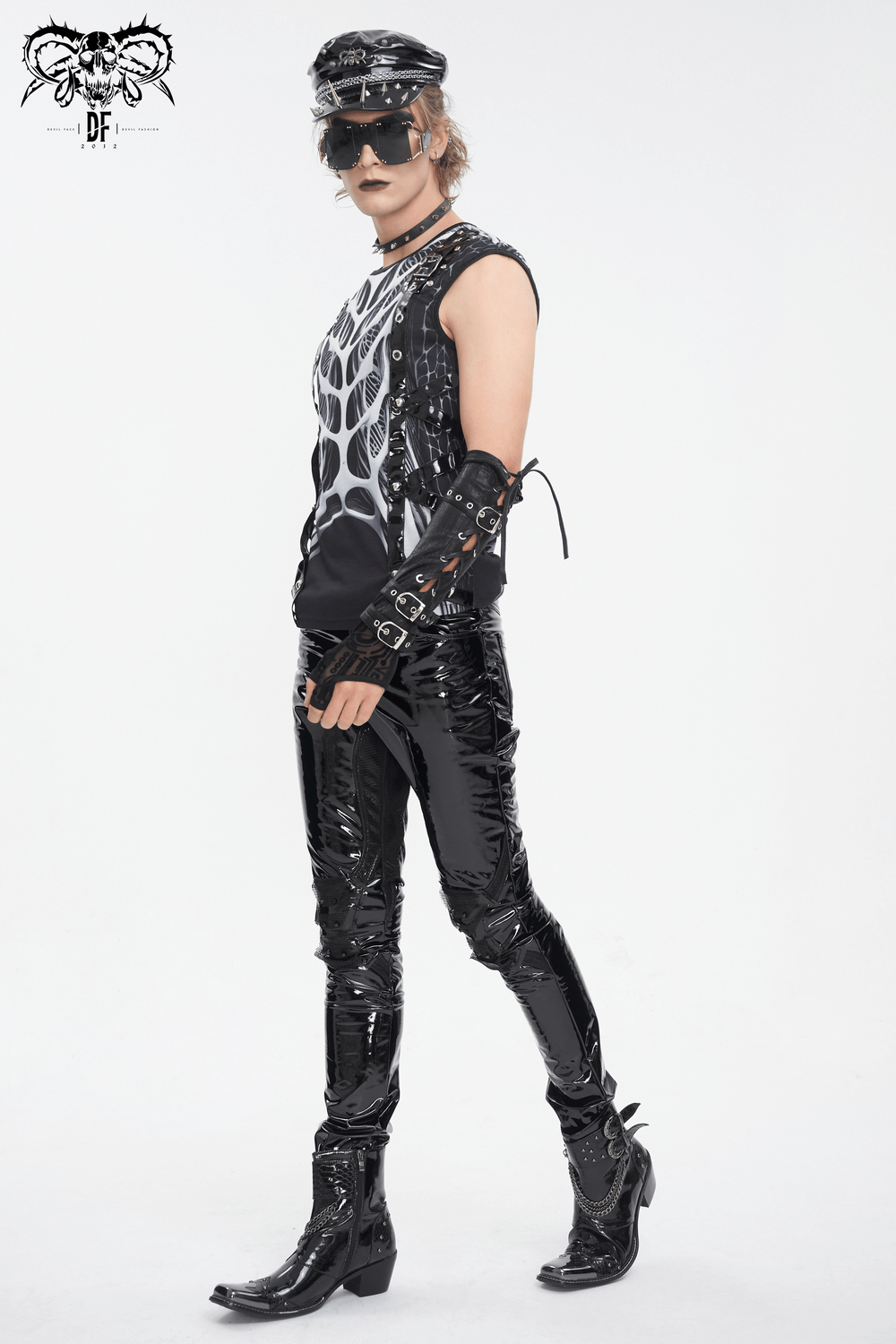 Gothic male model in black tank top with skeleton graphic and shiny pants, showcasing edgy rock-inspired style.