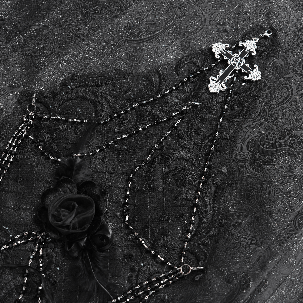 Close-up of gothic black maxi skirt showcasing lace, silver cross pendant, and rose chain details for dark elegance.