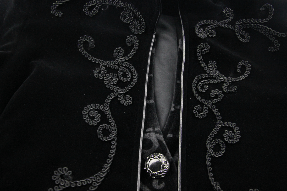 Close-up of intricate embroidery on a men's black velvet gothic tailcoat featuring stylish buttons.