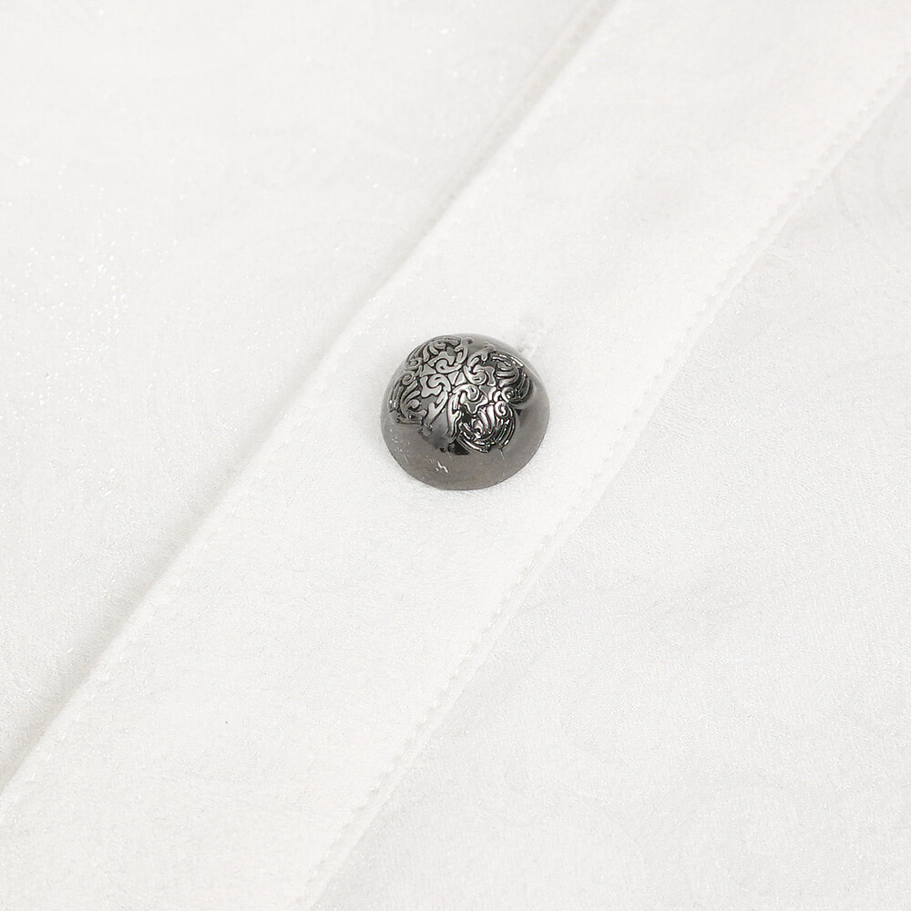 Close-up of a decorative button on a men's gothic shirt with floral embossing and a turn-down collar.