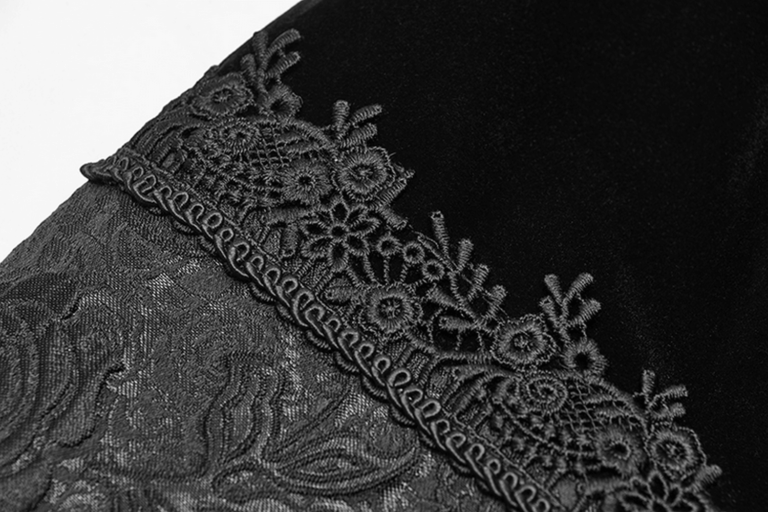 Close-up of black velvet and lace detailing on a Gothic men's cape, showcasing intricate jacquard patterns.
