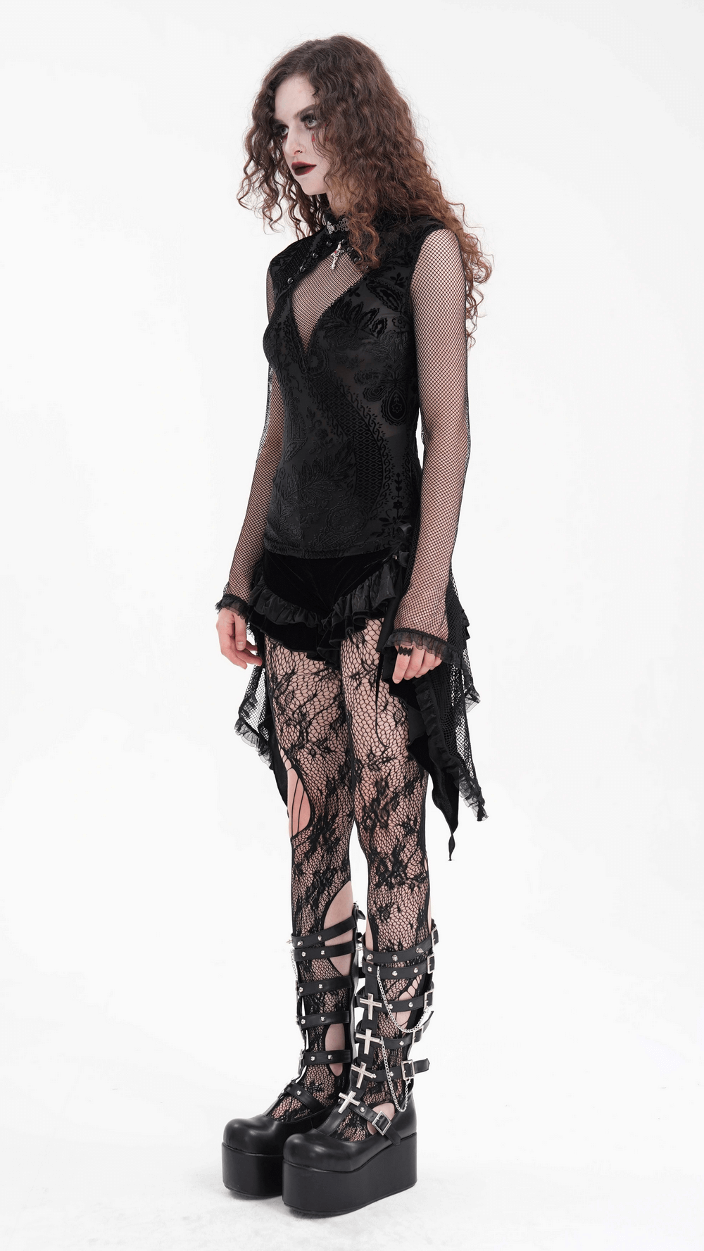 Gothic model showcasing a dramatic mesh sleeve top with lace, paired with edgy boots and intricate fishnet tights.