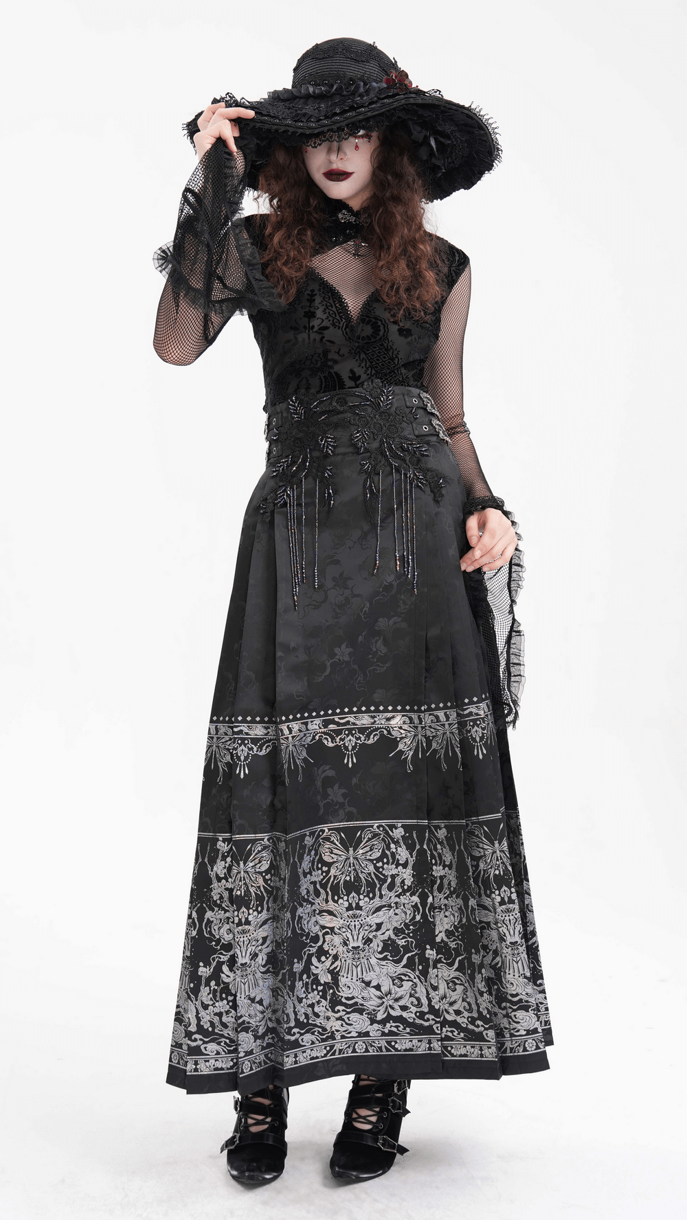 Gothic model in black mesh sleeve Victorian dress with lace details and wide-brimmed hat, showcasing dark elegance.