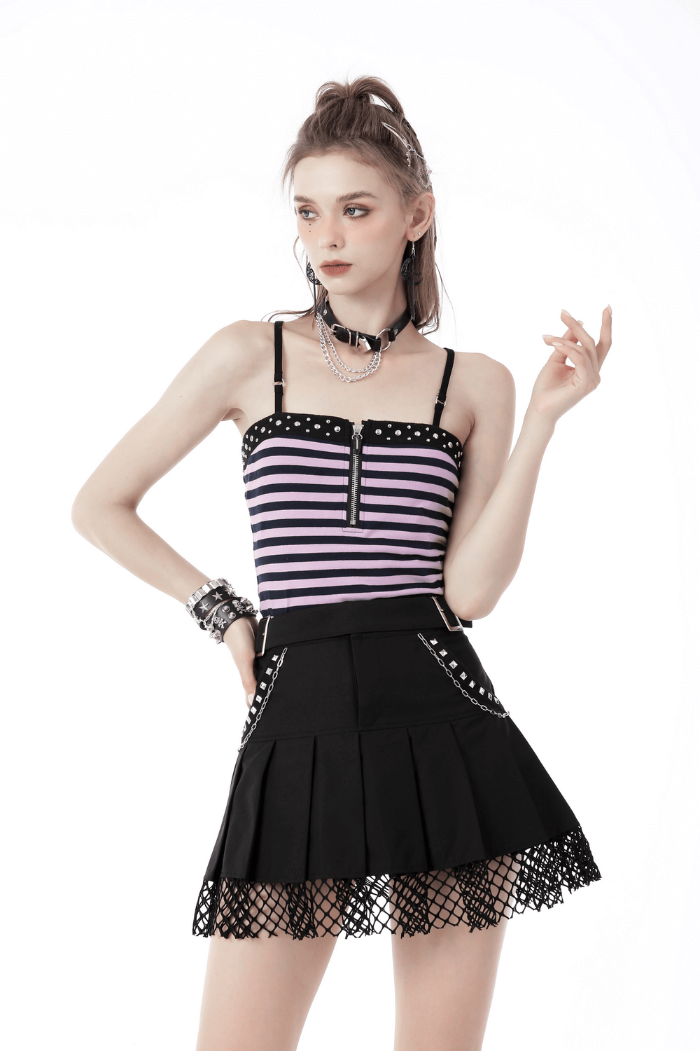 Edgy model wearing a pleated black mini skirt with studded details and a striped top, showcasing a rockstar style.