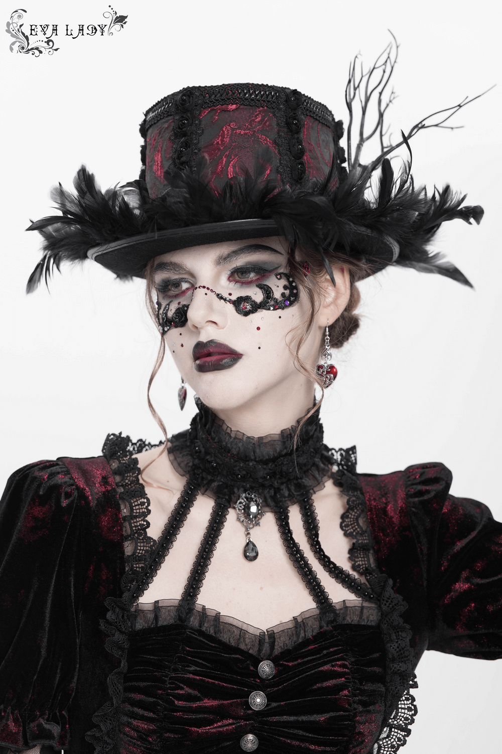Gothic mini top hat with black feathers and rose brocade, paired with Victorian-style attire and dramatic makeup.