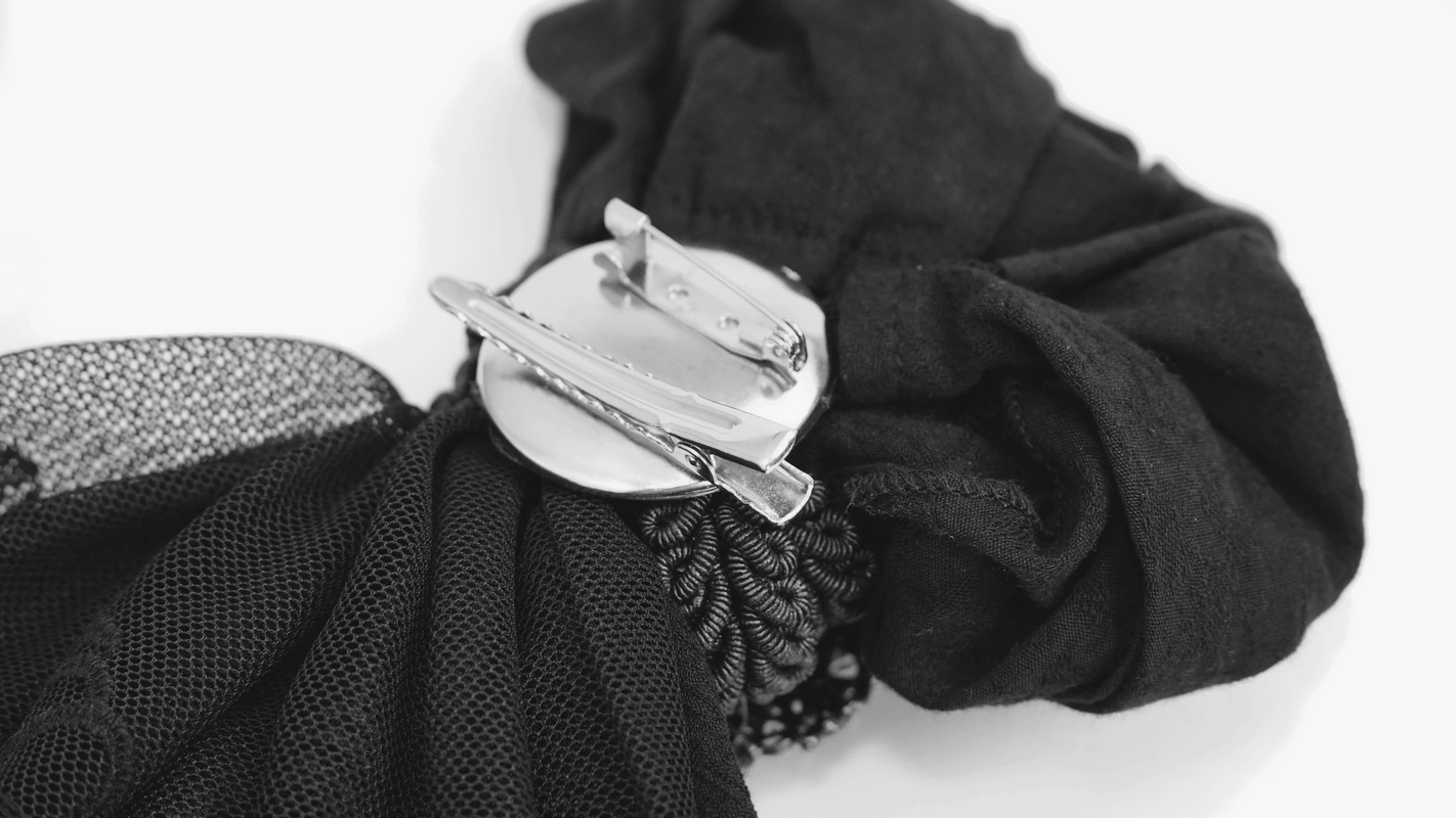 Close-up of a vintage gothic bow tie with a decorative brooch and detailed fabric design.