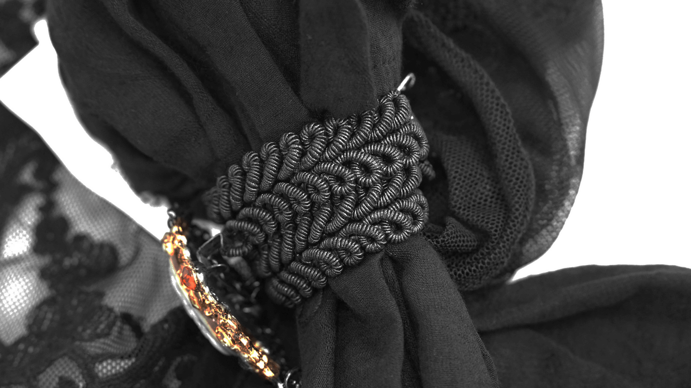 Close-up of a vintage Gothic bow tie with intricate black detailing and a decorative brooch.