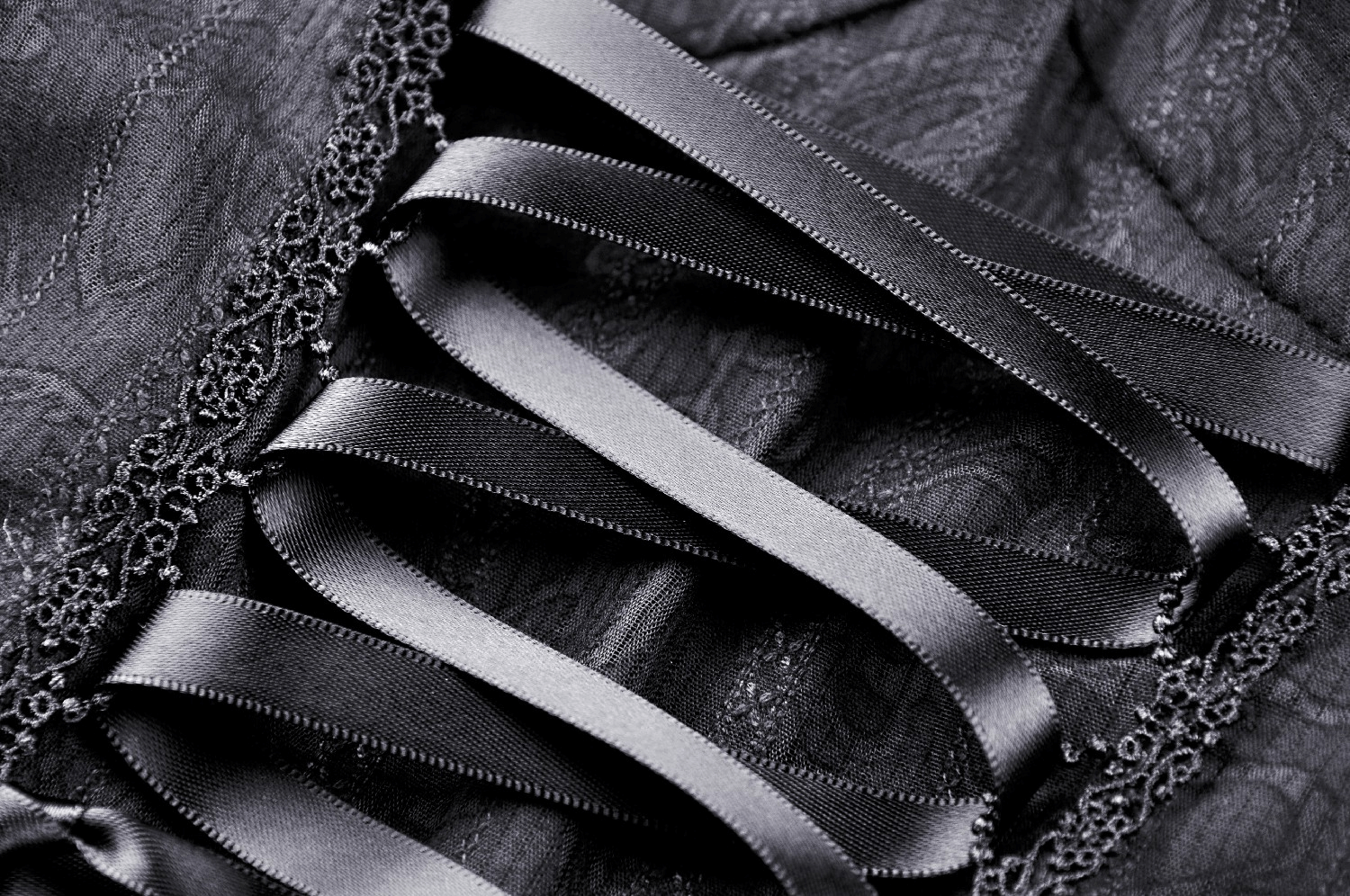 Close-up of elegant black lace-up corset ribbons on a gothic dress, showcasing intricate detailing.