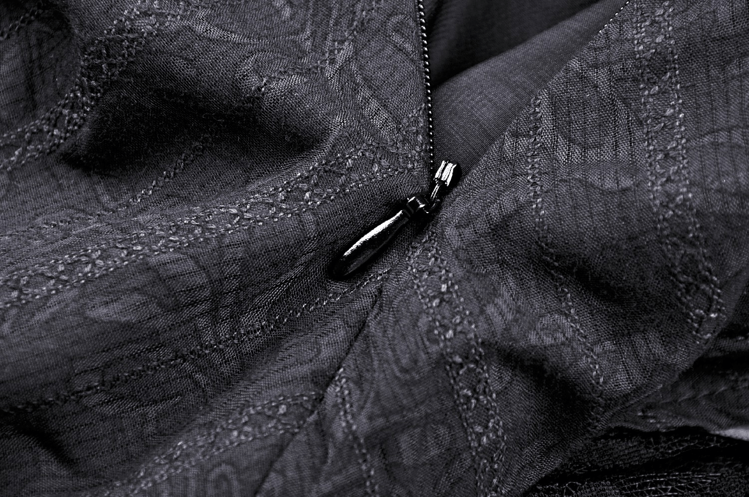 Close-up of a gothic black corset dress fabric with intricately woven patterns and a stylish zipper.