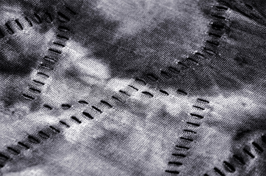 Close-up of a gothic off-shoulder top's fabric featuring dark tie-dye and edgy stitching details.