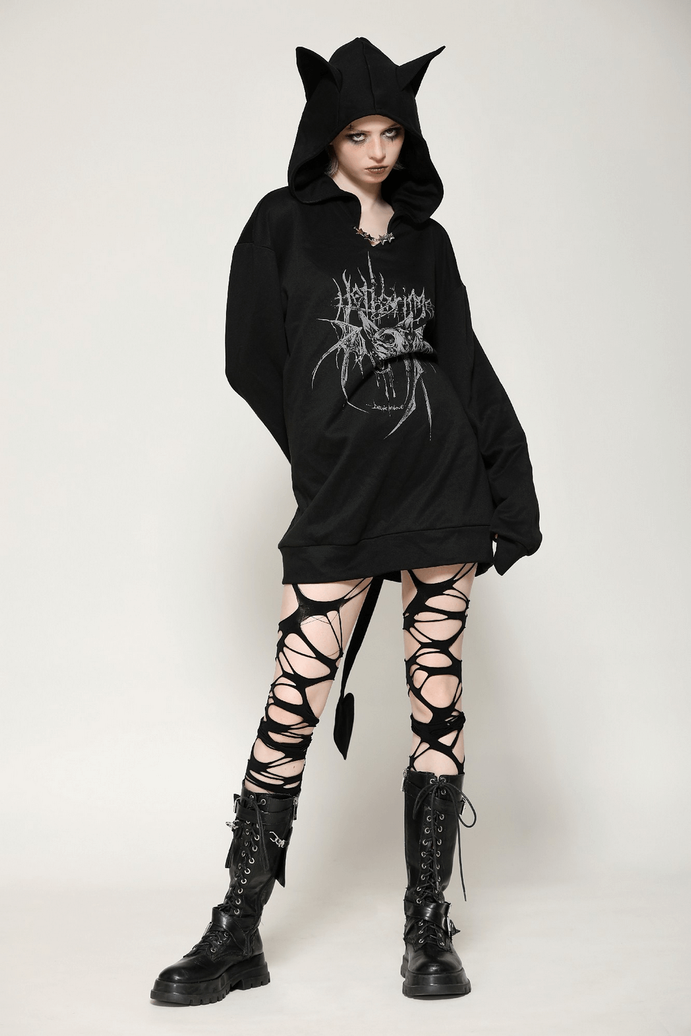 Model showcasing a gothic oversized hoodie with cat ears and devil tail, paired with edgy lace-up leggings and combat boots.