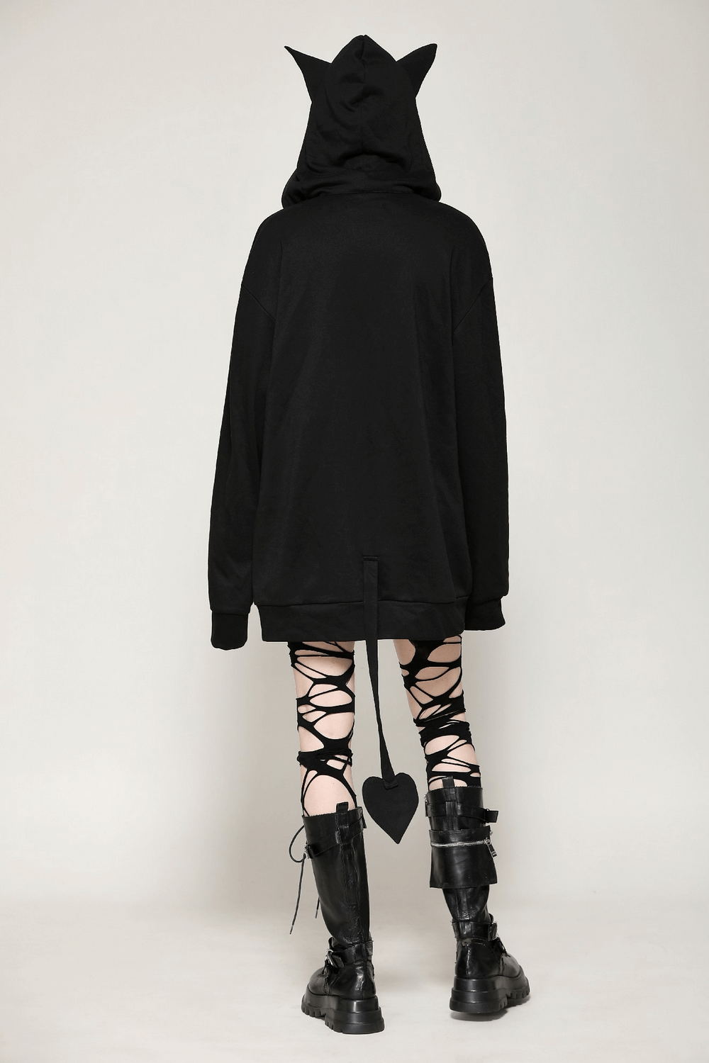 Back view of a gothic oversized black hoodie with cat ears and heart-shaped tail, paired with lace-up leggings and boots.