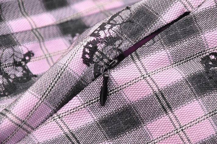 Close-up of gothic plaid fabric with black lace details and zipper, showcasing punk elegance.