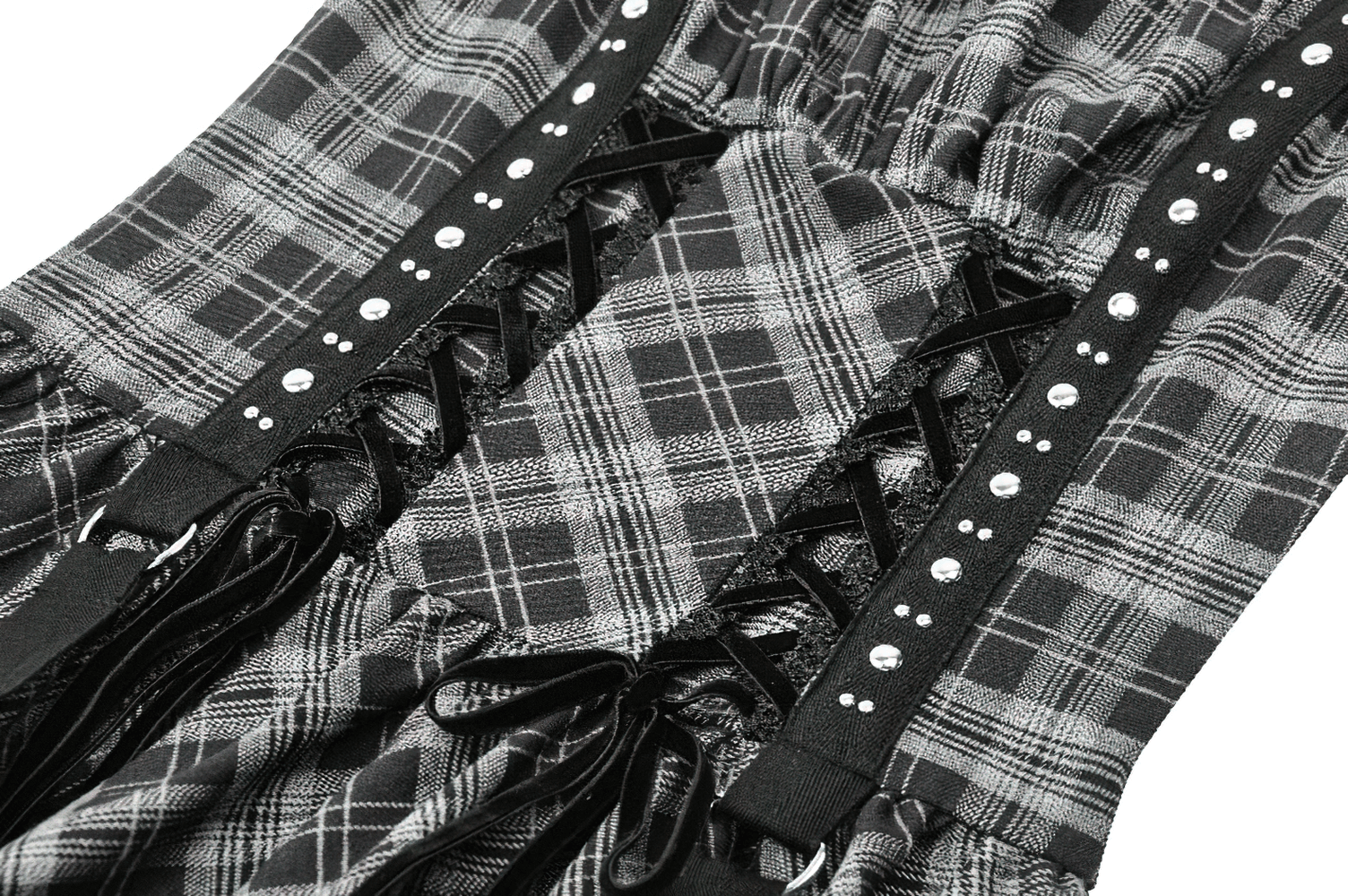 Close-up of gothic plaid mini dress showing lace-up corset detail with studded harness straps and ruffled edges.