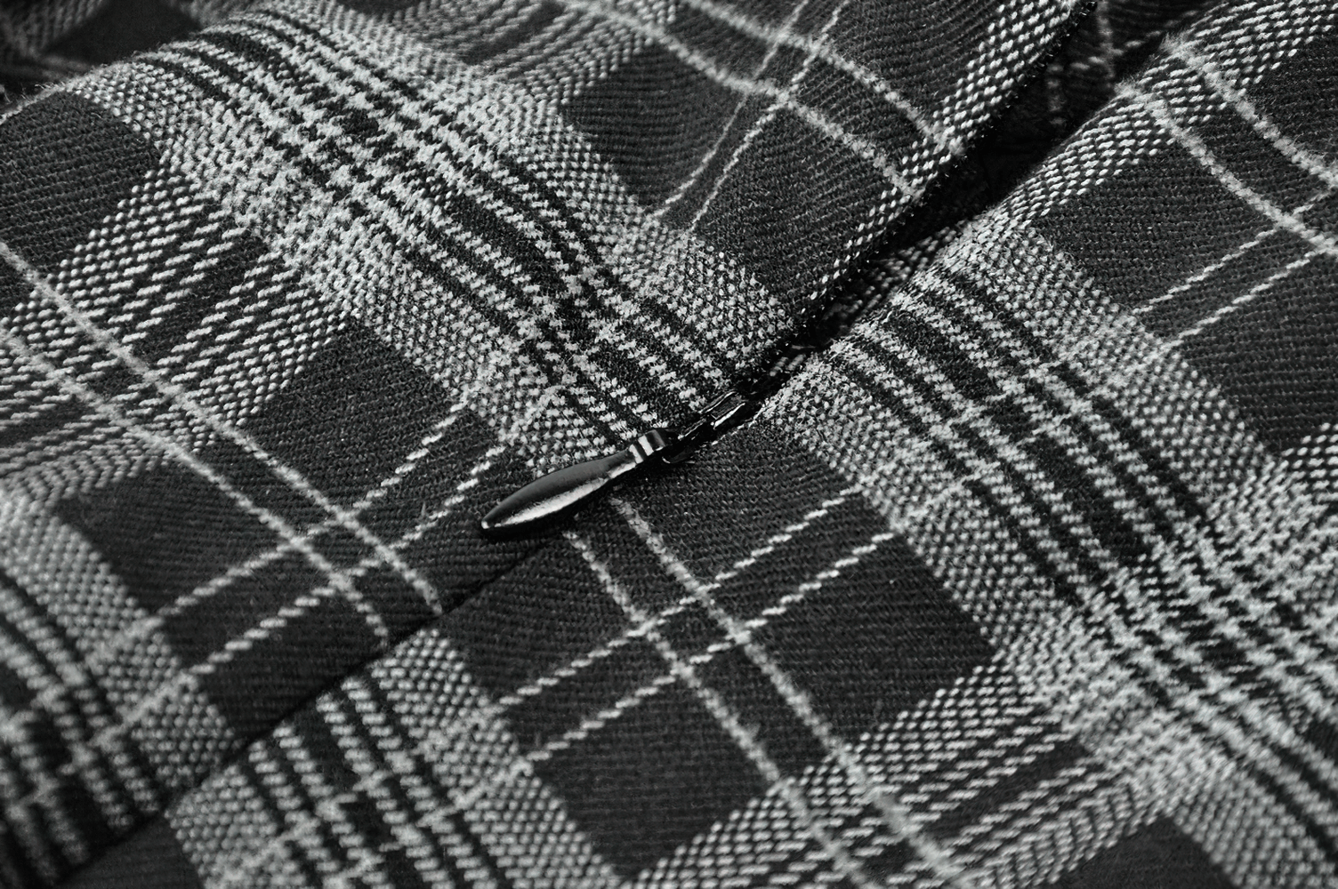 Close-up of gothic plaid fabric featuring black and gray check pattern with a zipper detail.