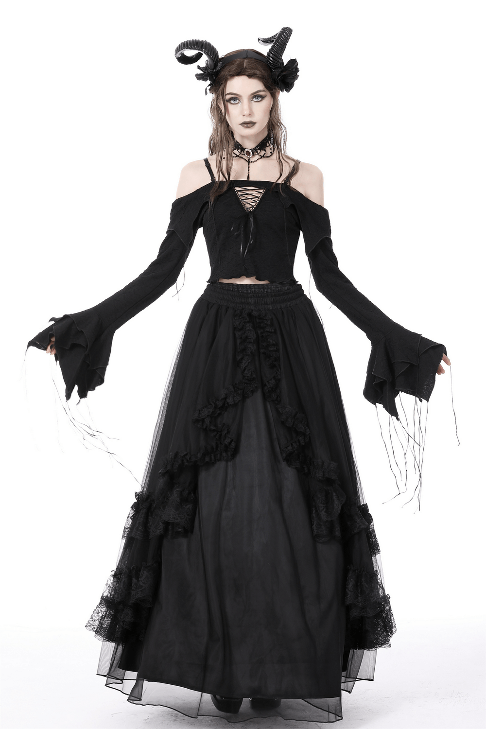 Gothic woman in an off-shoulder black crop top and long layered skirt, showcasing steampunk style and dramatic sleeves.