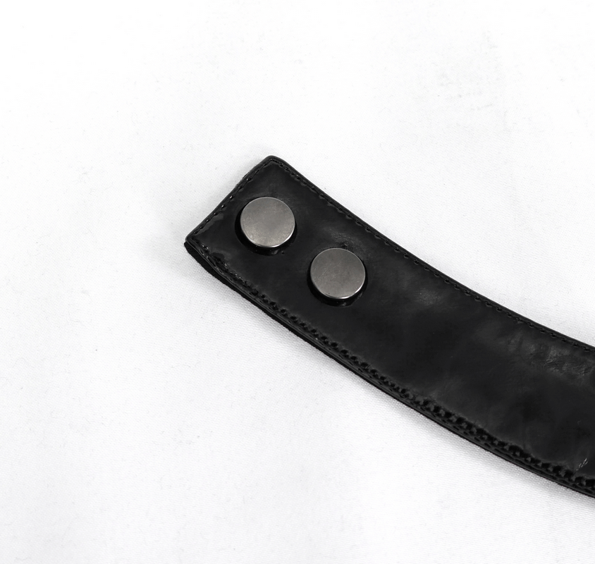 Close-up of black leather strap with metal snap buttons for adjustable gothic fashion.