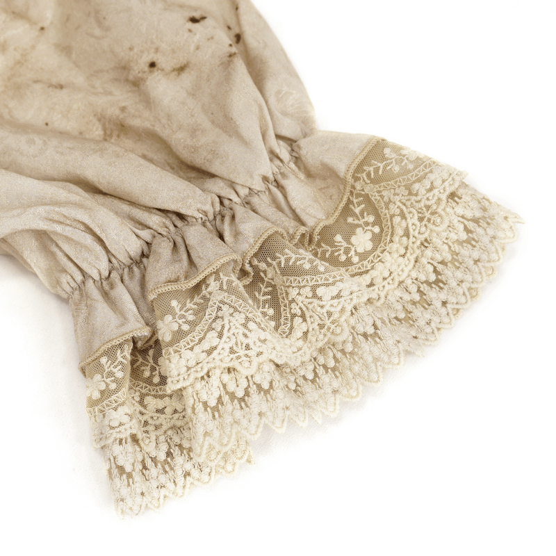 Close-up of vintage lace detailing on a sleeve with elegant ruffles and floral patterns.