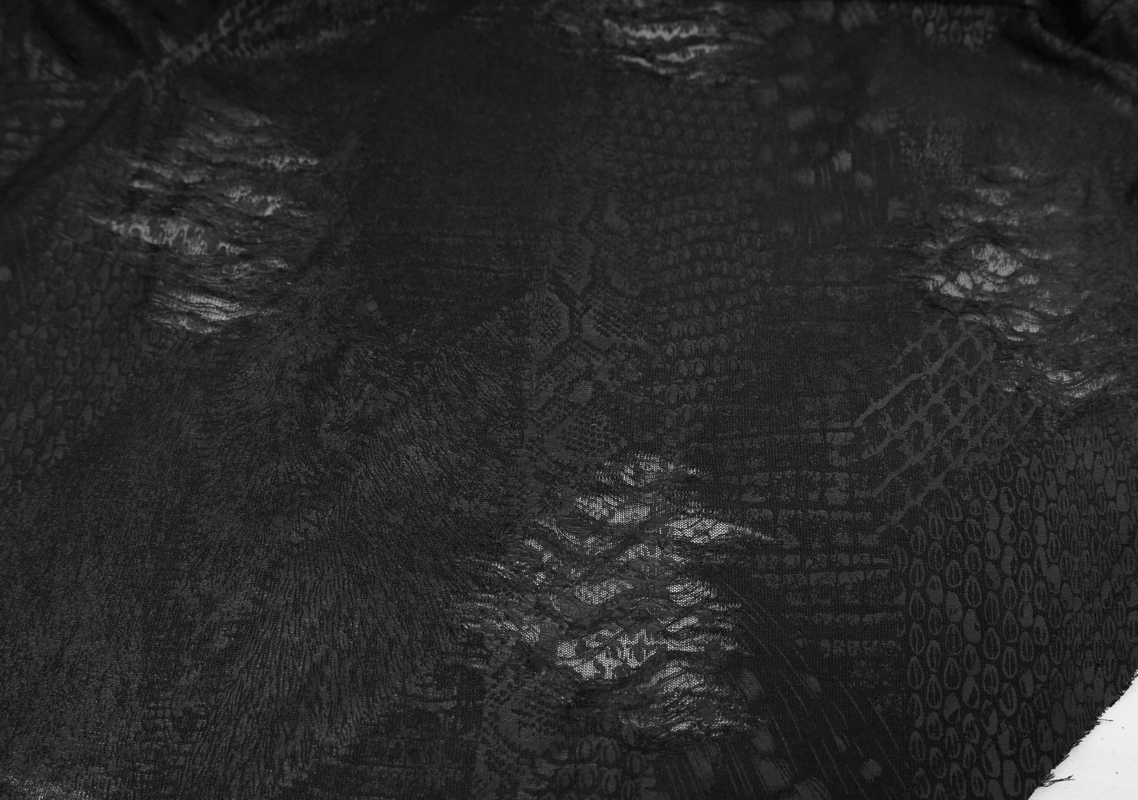 Close-up of black textured fabric featuring unique patterns and distressed details for a gothic-style cape.