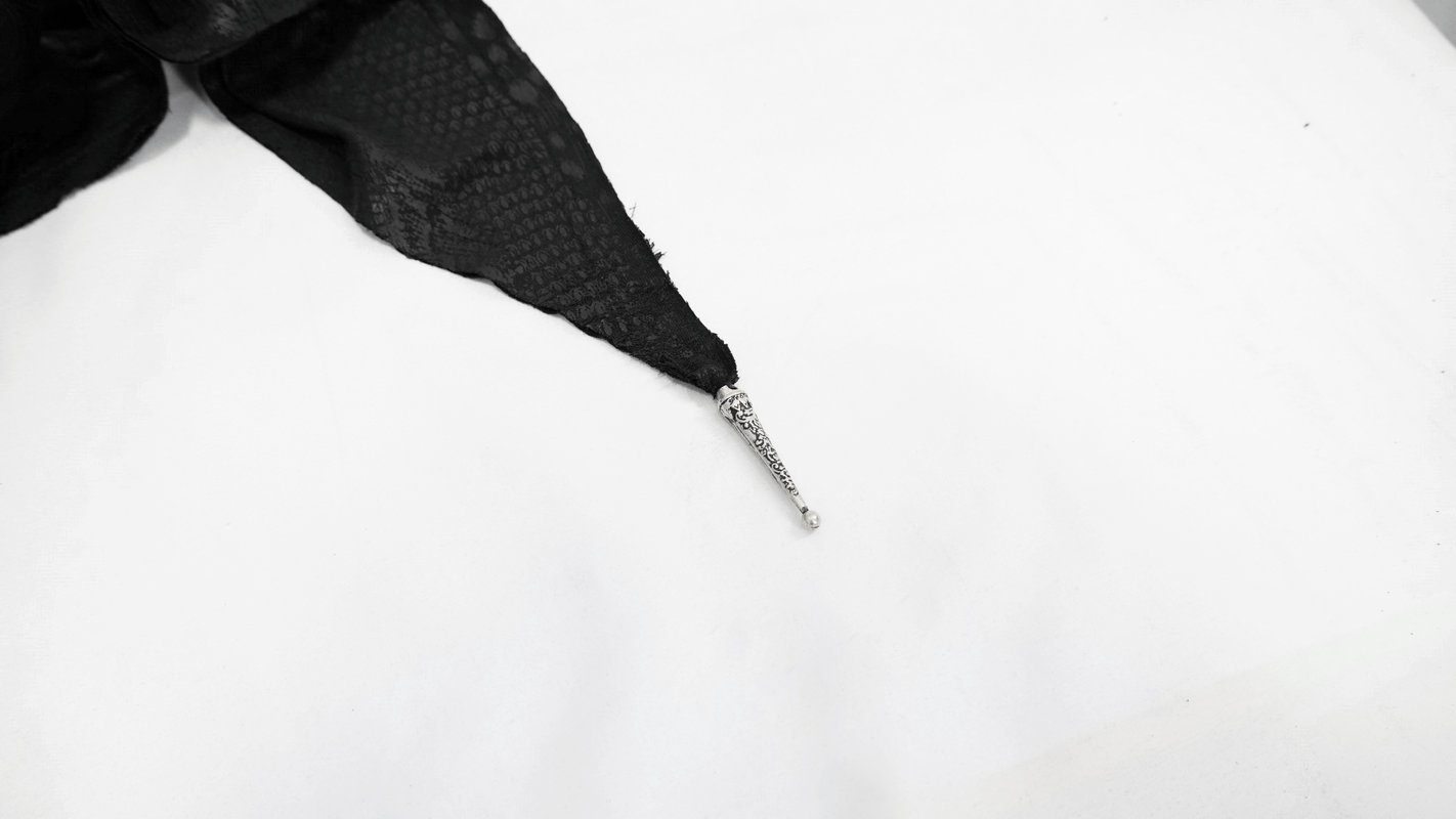 Close-up of lace-up detail on black gothic asymmetrical cape, showcasing elegant design and vintage style.