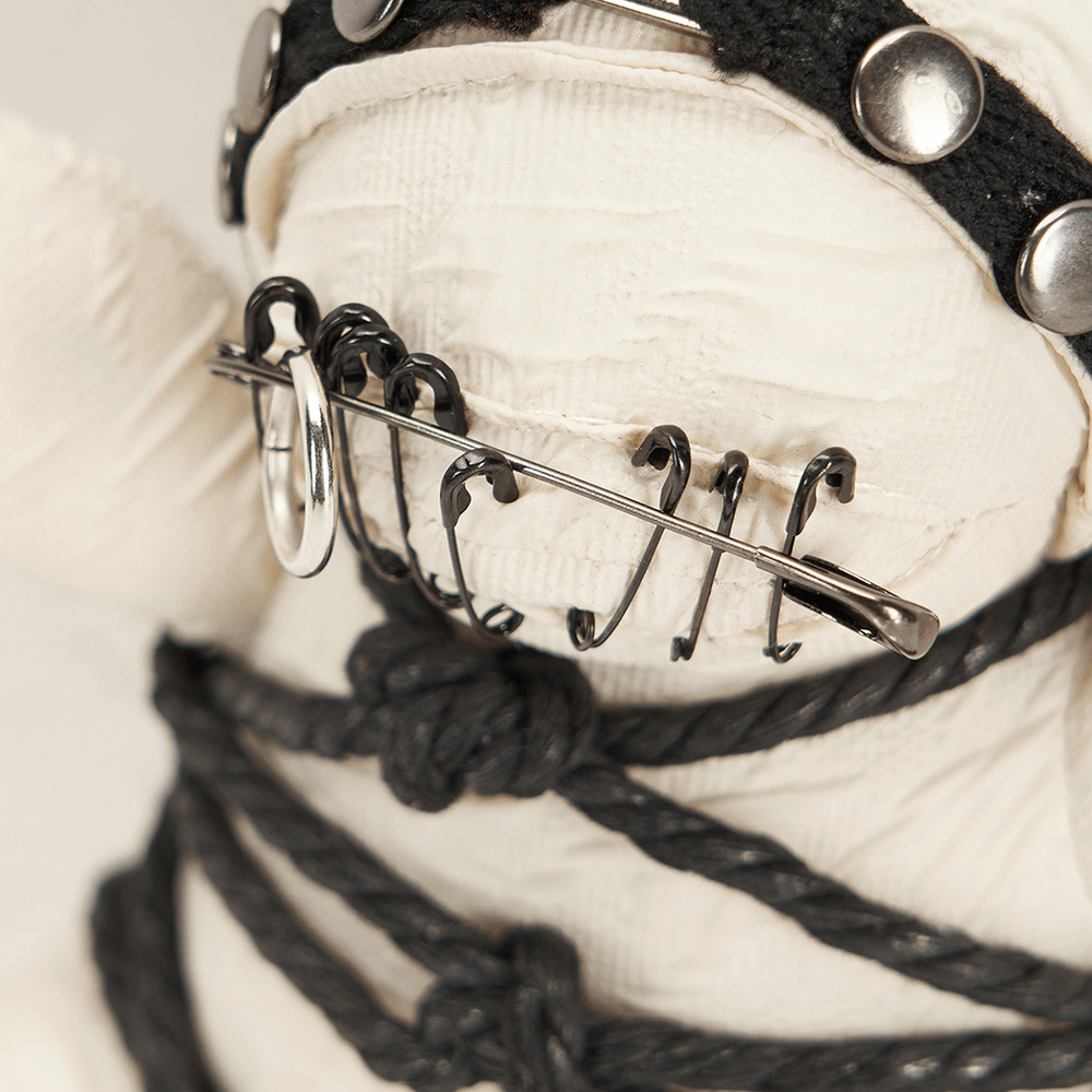 Close-up of Gothic bear plush showcasing edgy safety pin and chain details on textured fabric.