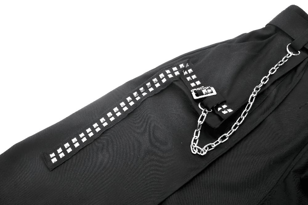 Close-up of gothic punk skirt detail featuring chains, buckle, and studded accents on black fabric.