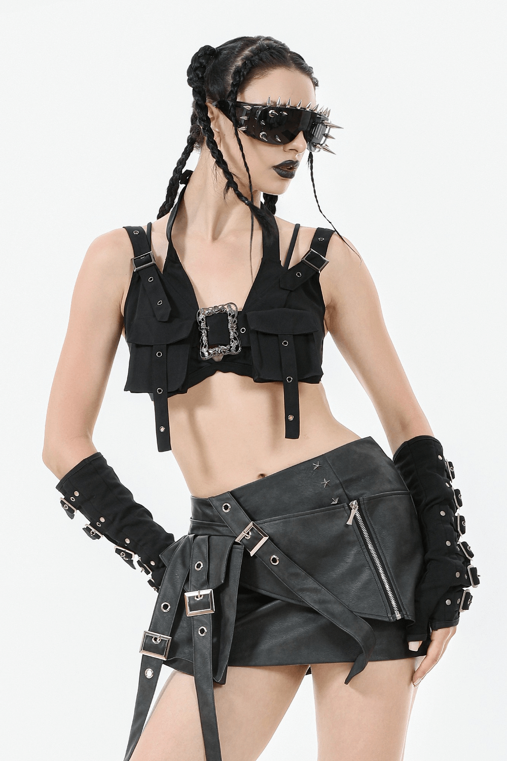Gothic punk model in black faux leather mini skirt with buckle straps, paired with edgy black vest and accessories.