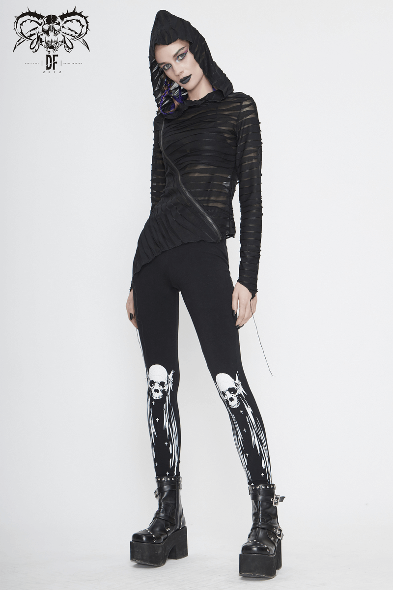 Stylish woman in black skull leggings and layered black hoodie, showcasing punk alternative fashion.