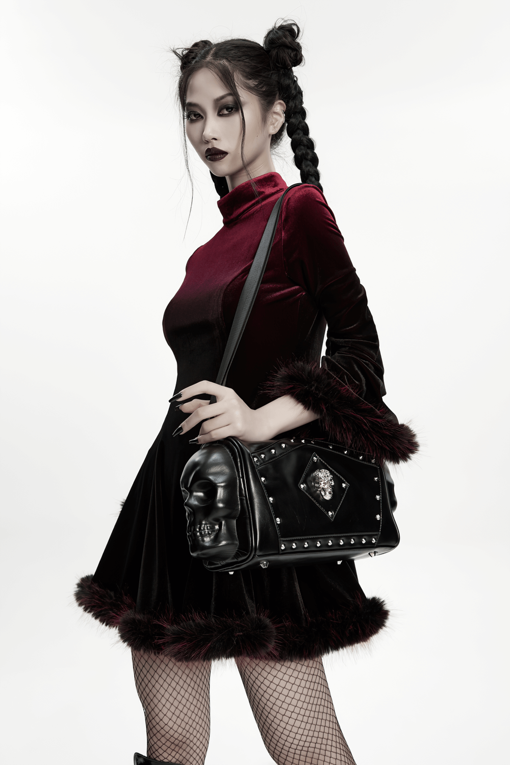 Gothic punk model in velvet dress holding coffin skull shoulder bag with rivets, showcasing dark fashion style.
