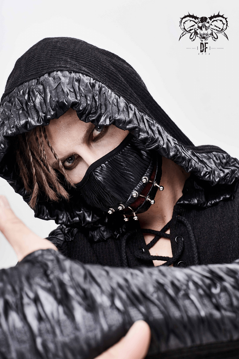 Gothic punk male model wearing a black cyberpunk mask with piercing rings and a stylish hooded outfit.