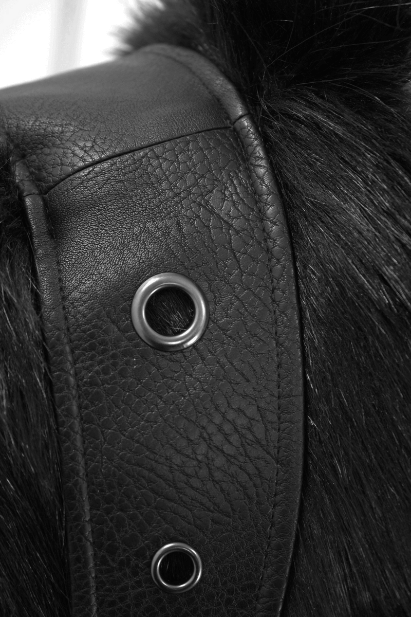 Close-up of gothic punk coat's black leather and fur texture with decorative silver button detail.