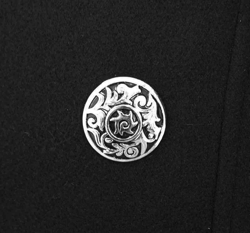 Close-up of a silver decorative button on a black gothic punk coat showcasing intricate design.