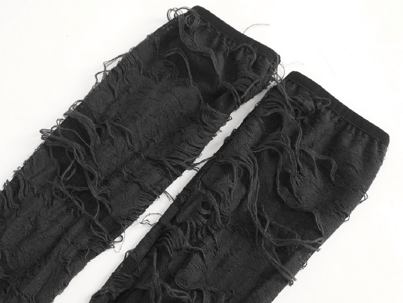 Close-up of dramatic black ripped long gloves, featuring intricate frayed detailing for a gothic punk style.