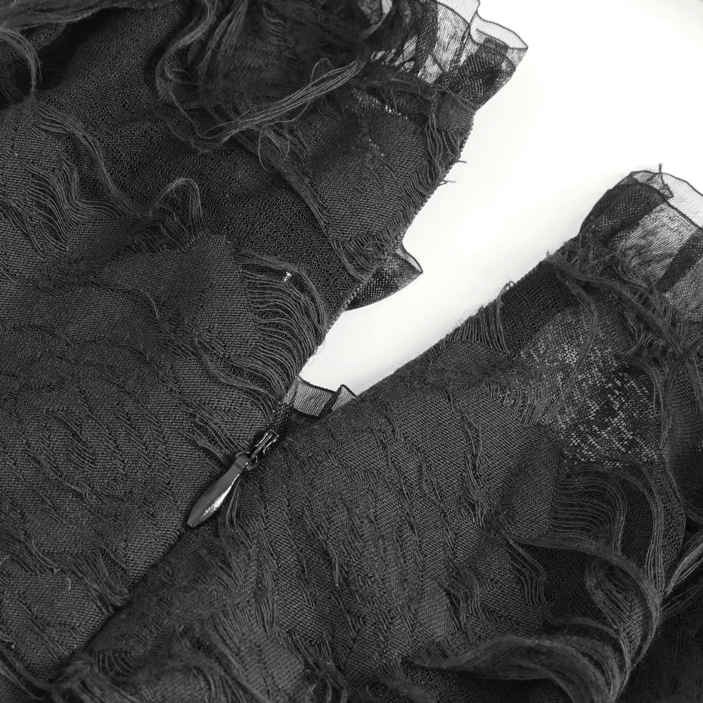 Close-up of black ripped fabric and long gloves, showcasing a gothic punk style with dramatic texture.