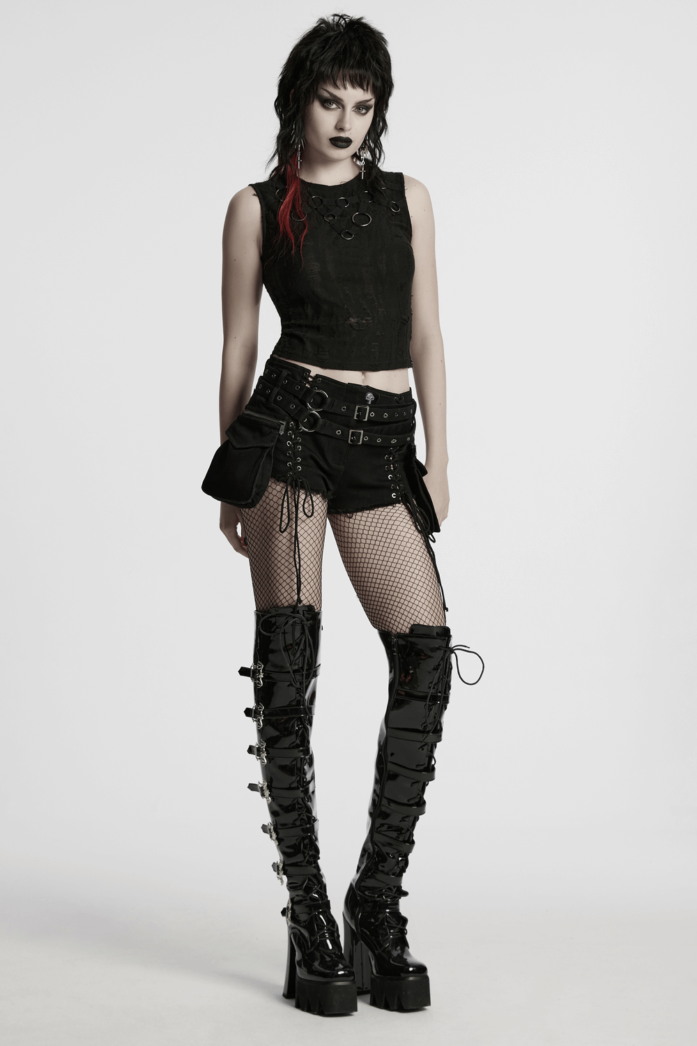 Gothic punk model wearing lace-up black shorts with double belt detail and fishnet stockings, showcasing edgy street style.