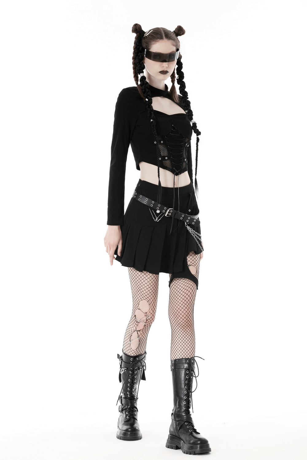 Gothic punk model in black mesh crop top, pleated skirt, fishnet tights, and stylish combat boots.