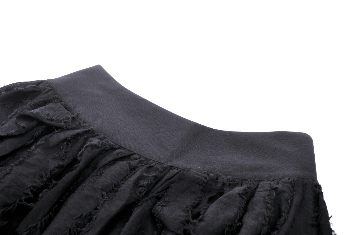 Close-up of a black gothic punk mini skirt with edgy fringe accents and a smooth waistband.